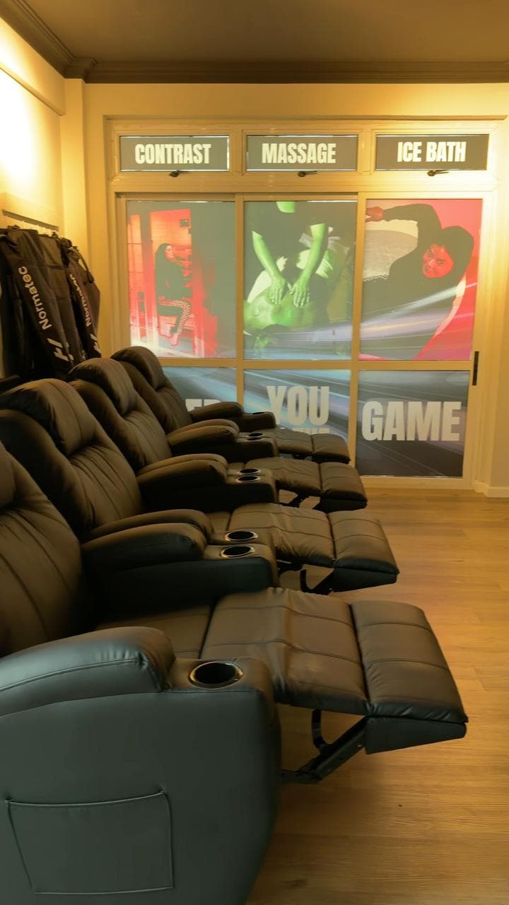 Banera’s compression lounge: recliners and Normatec boots, with the contrast, massage and ice bath rooms behind